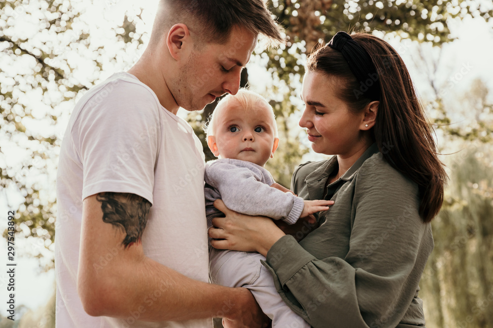 Family bonds. Happy young family of three smiling while spending free time outdoors Family bonds. Happy young family of three smiling while spending free time outdoors