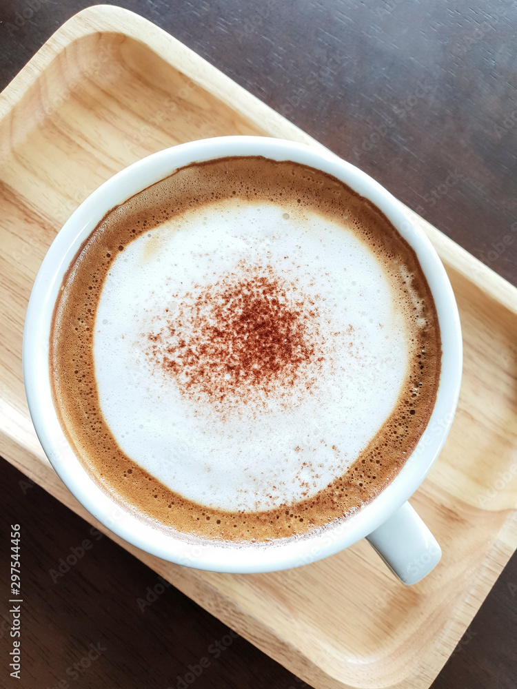 A cup of coffee is placed on a wooden tray. A cup of coffee is placed on a wooden tray.