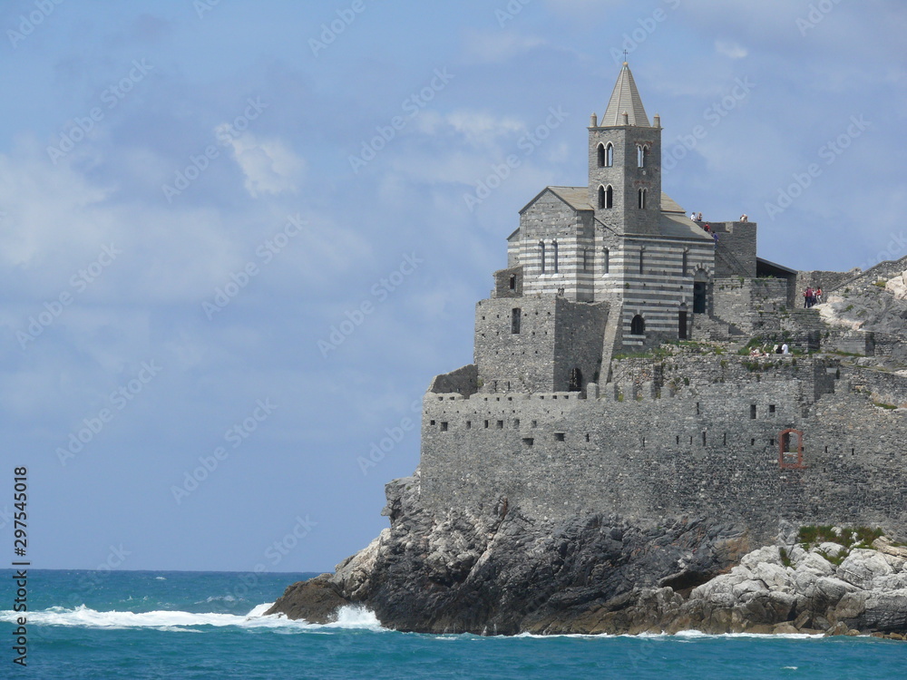 Church of San PIetro in Portovenere, built on a rock overlooking the sea. Sky with clouds and blue sea waves.