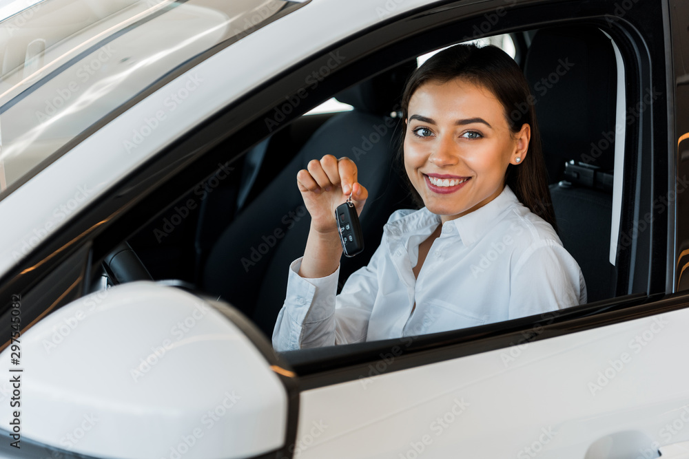 selective focus of happy woman holding car key while sitting in car selective focus of happy woman holding car key while sitting in car
