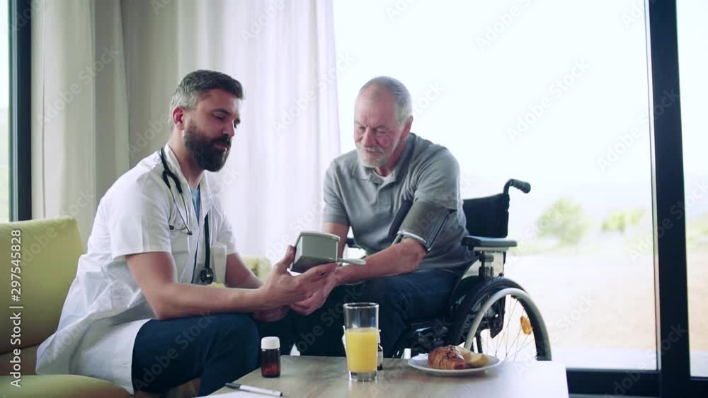 Health visitor and a senior man in wheelchair during home visit. Health visitor and a senior man in wheelchair during home visit.