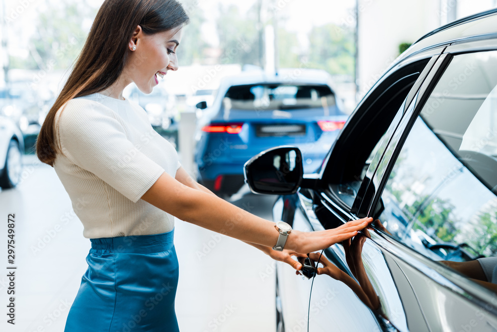 © LIGHTFIELD STUDIOS - side view of excited young woman looking at black car