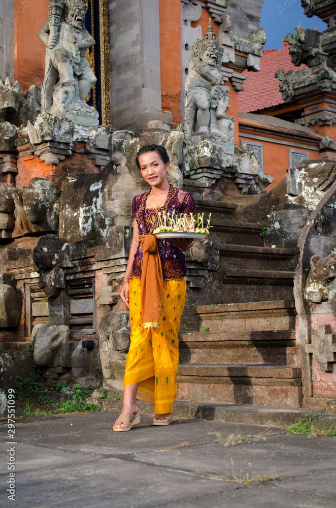 Beautiful balinese girl praying in temple and dressed in a traditional clothing (Pura Puseh Seraya, Bali).