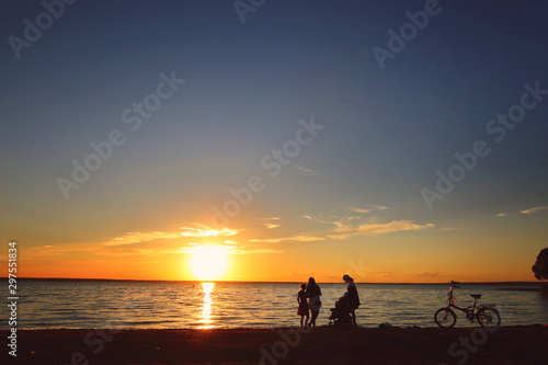 People, children, women, bike on the lake at sunset