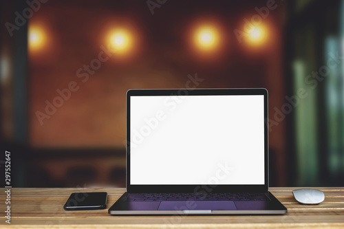 Laptop computer with blank white screen on the table, background wall blur