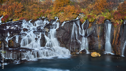 Stunning smooth waterfall background with yellow leaf at Hraunfossar, Iceland during autumn season © hafizanwar