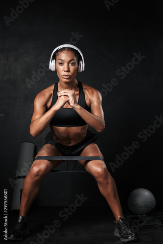 Image of focused african american woman doing sit-ups with expander