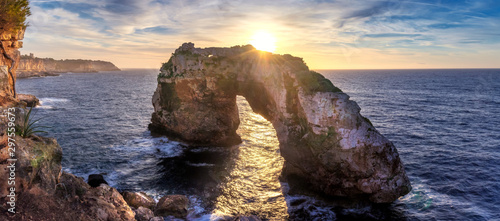 Natural arch in the mediterranean sea, sunrise with golden sunbeam and beautiful colourful sky, Santanyi, Mallorca, Spain. photo