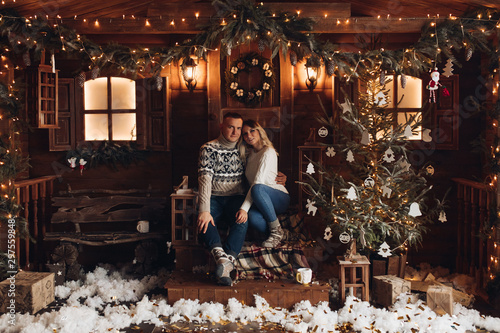 Christmas portrait of a romantic couple. Guy hugs the girl and kisses. They sit in a beautiful house. Christmas mood of lovers on the background of decorative snow and flying serpentine. Studio photo © Вячеслав Косько
