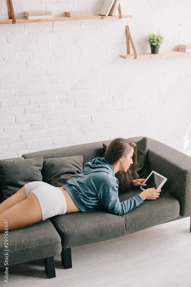 attractive woman in panties using digital tablet while lying on sofa attractive woman in panties using digital tablet while lying on sofa