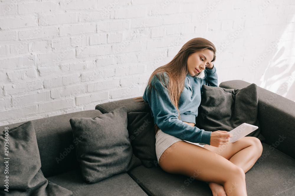 attractive pensive girl in panties using digital tablet on sofa attractive pensive girl in panties using digital tablet on sofa