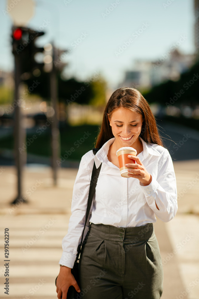Young businesswoman drinking coffee on the street	