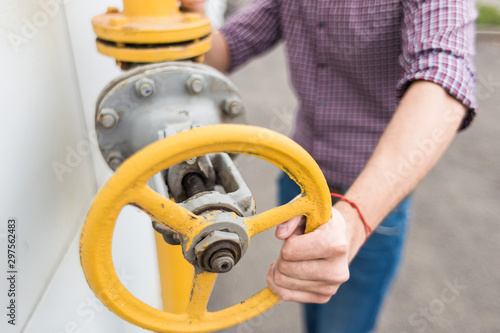 power station worker. man engineer in helmet and shirt twist gas pipe valve