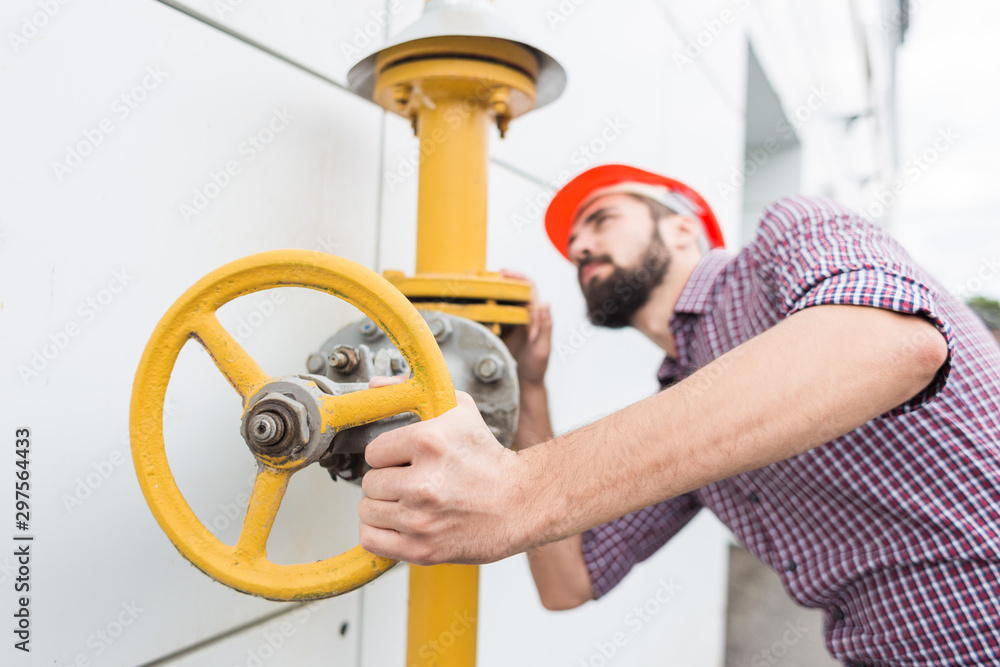 power station worker. man engineer in helmet and shirt twist gas pipe valve power station worker. man engineer in helmet and shirt twist gas pipe valve