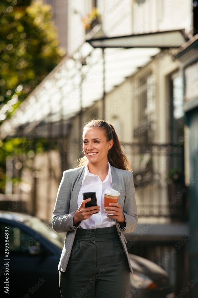 Young woman in city using phone on coffee break