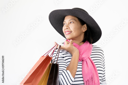 Beautiful Asian women wearing black hats and pink scarf smiling and happy, carrying many shopping bags. Shopping happily in the mall during the festive season Black Friday, Christmas, and New Year