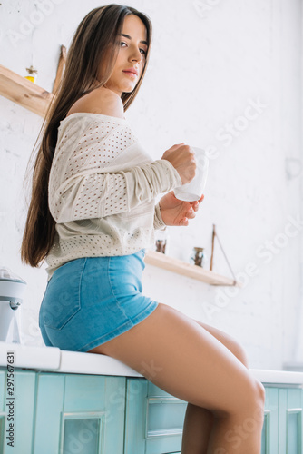 beautiful girl with long hair holding cup of tea in kitchen