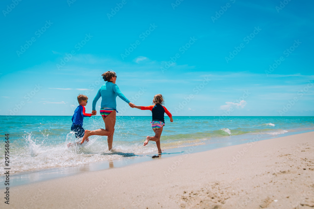 mother with kids play with water run on beach