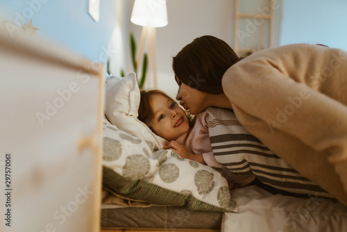 Obraz na plátně Mother kisses her daughter before bedtime