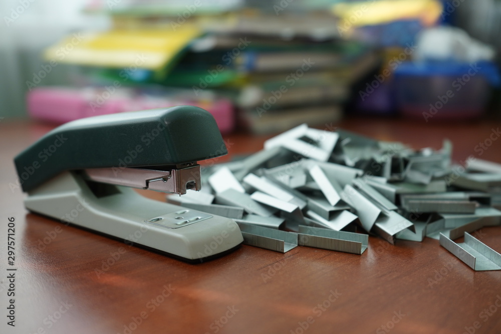 Many clips for a stapler on a wooden table. Stapler with a bunch of paper clips on the table. Many clips for a stapler on a wooden table. Stapler with a bunch of paper clips on the table.