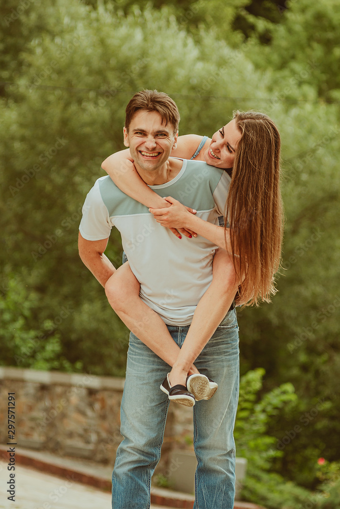 beautiful young couple in love decided to walk along the park alley - hugging, fooling around. A date, time spent together is beautiful young couple in love decided to walk along the park alley - hugging, fooling around. A date, time spent together is