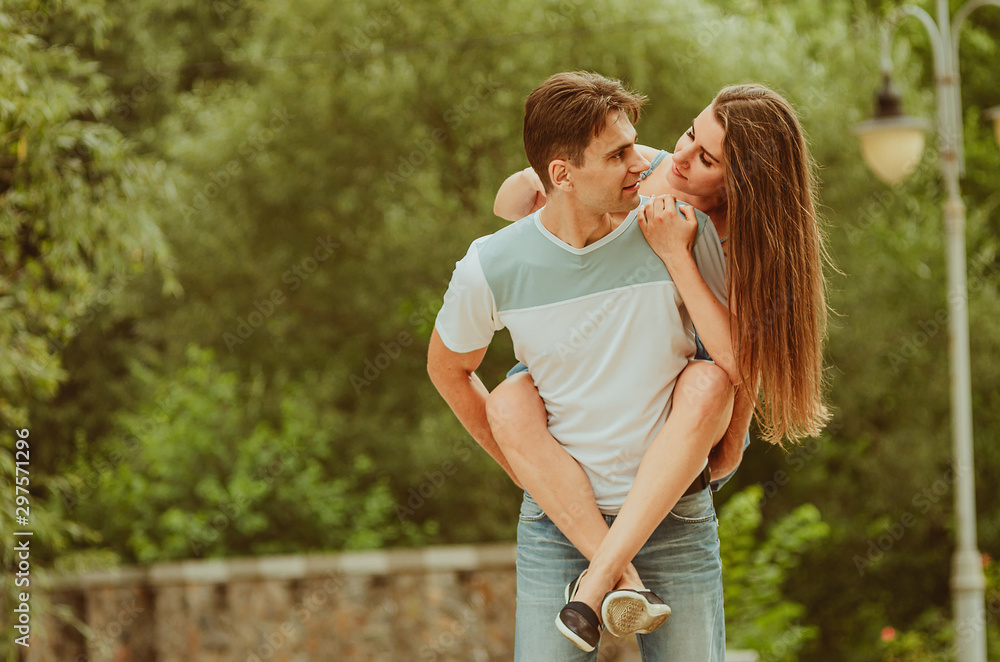 Fototapeta premium beautiful young couple in love decided to walk along the park alley - hugging, fooling around. A date, time spent together is