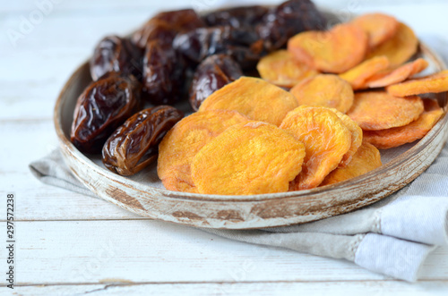 Dried dates and dried apricots on a white wooden background