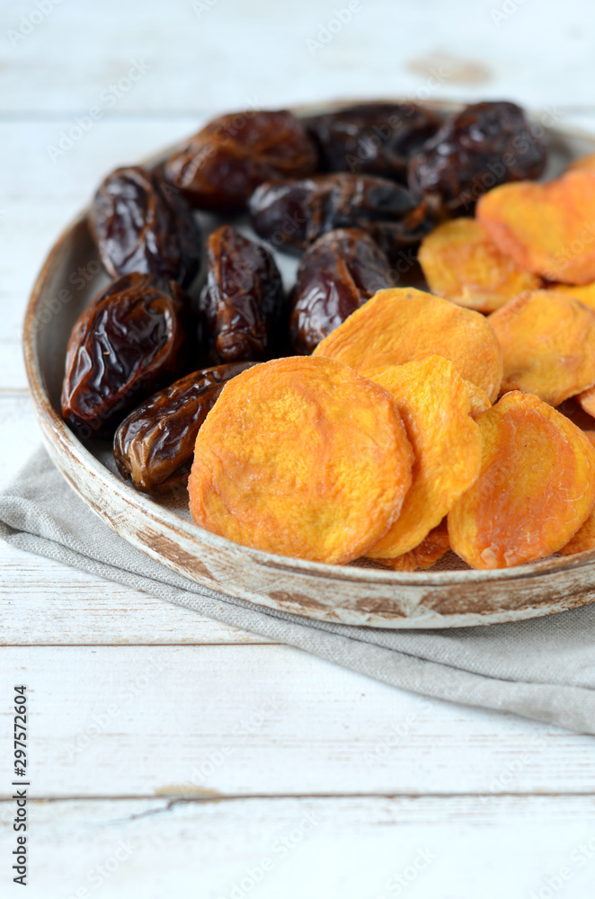 Fototapeta premium Dried dates and dried apricots on a white wooden background