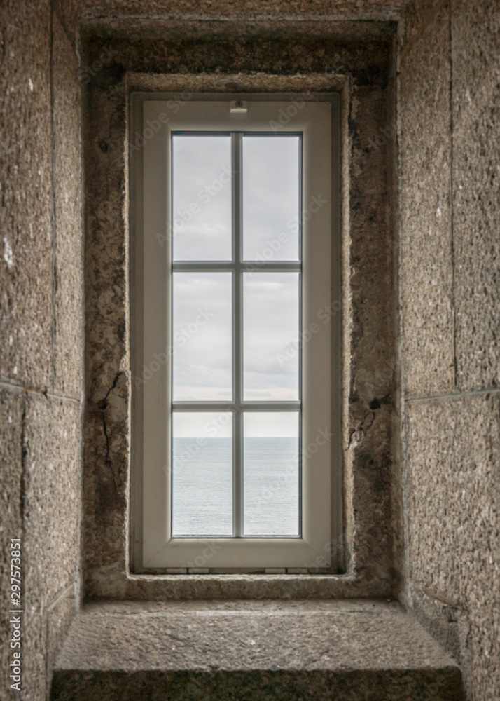 view of the ocean through a lighthouse window in the stone staircase