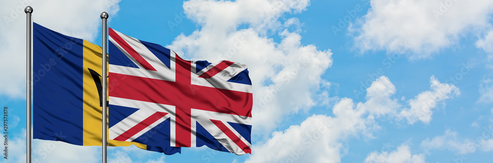 Barbados and United Kingdom flag waving in the wind against white cloudy blue sky together. Diplomacy concept, international relations. Barbados and United Kingdom flag waving in the wind against white cloudy blue sky together. Diplomacy concept, international relations.