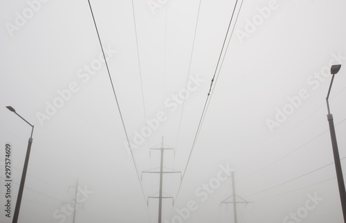 The electric pole and wires in front of gray foggy cloud. Concept of minimalist photo