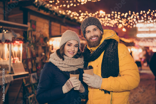 Photo of two people couple guy lady hot beverage in hands x-mas night spend time magic land newyear shopping market picking presents for parents wear jackets outside