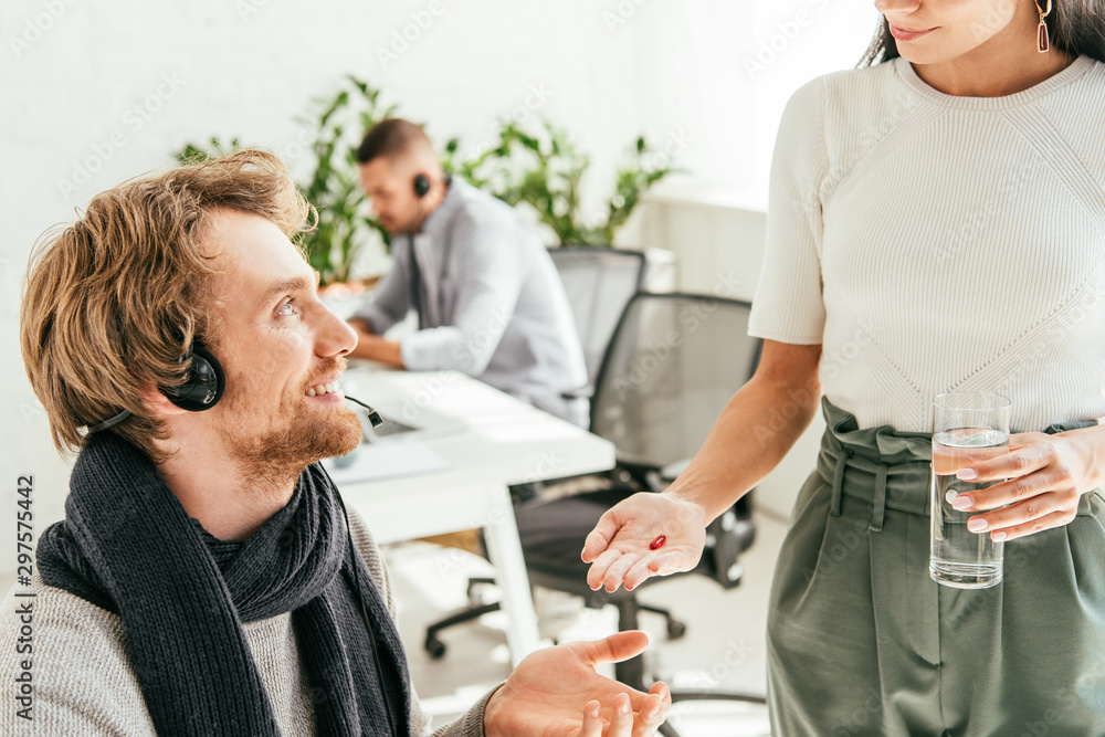 cropped view of broker giving pill to sick coworker in office cropped view of broker giving pill to sick coworker in office