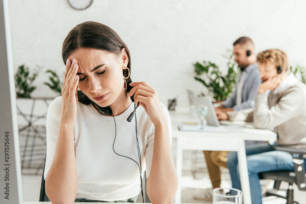 attractive broker with headache near coworkers in office attractive broker with headache near coworkers in office
