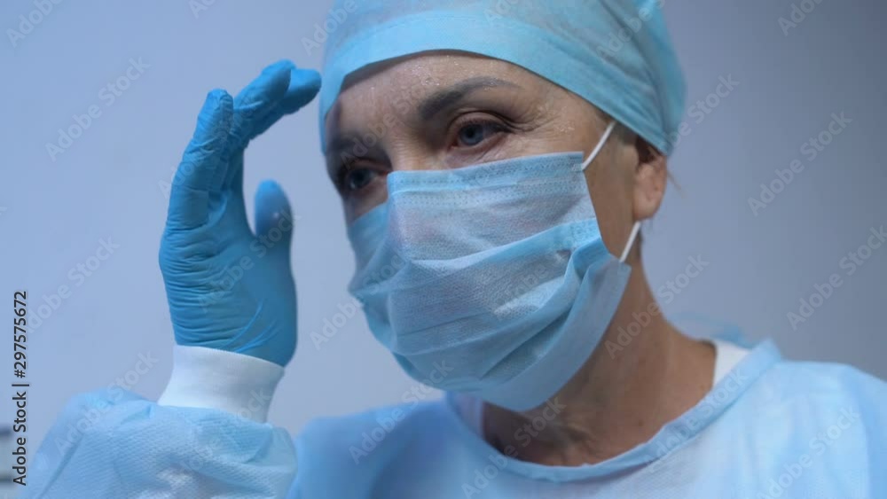Sweaty female surgeon wiping forehead after exhausted operation, life saving Sweaty female surgeon wiping forehead after exhausted operation, life saving
