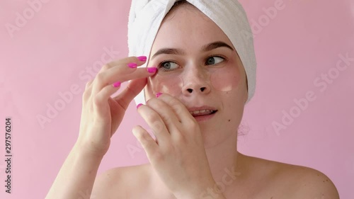 Young Woman with collagen pads under her eyes on pink background. Spa, skincare, beauty, cosmetics, wellness concept