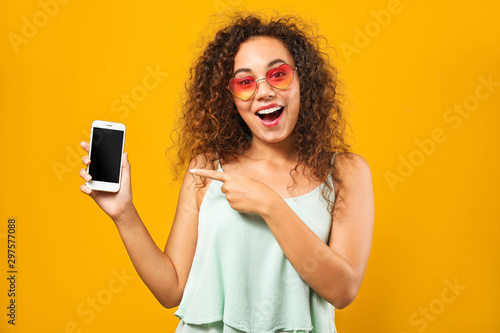 Portrait of happy African-American woman with mobile phone on color background