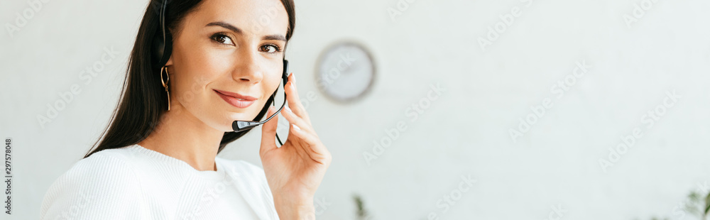 panoramic shot of beautiful broker touching headset while looking at camera panoramic shot of beautiful broker touching headset while looking at camera