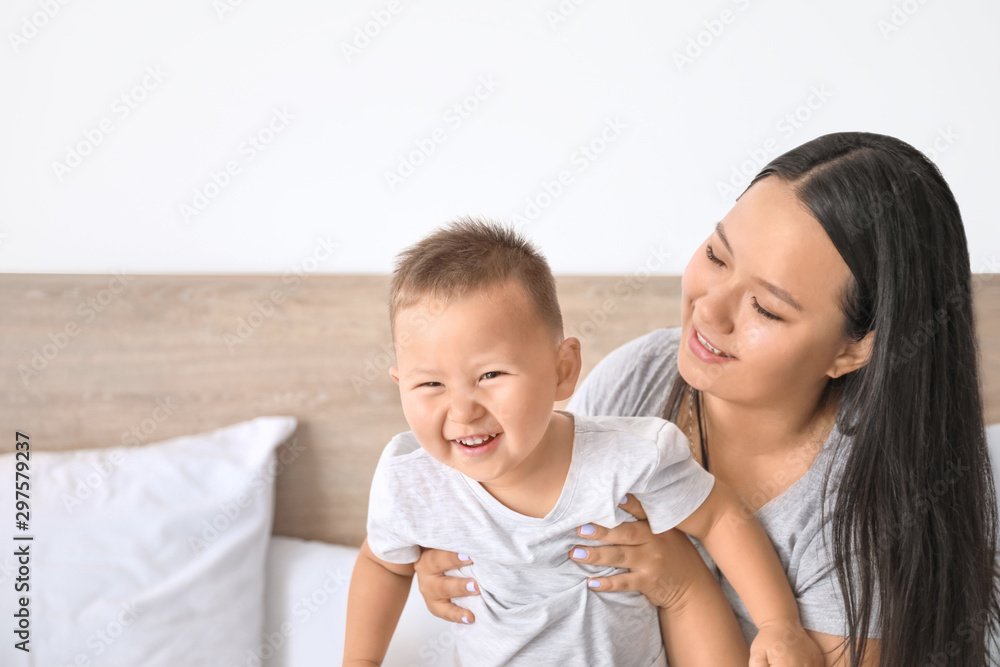 Asian mother and cute little baby playing on bed Asian mother and cute little baby playing on bed