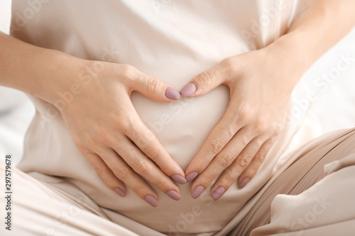 Beautiful young pregnant woman making heart with her hands, closeup