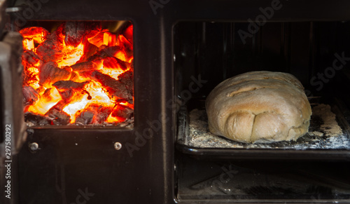 freshly baked bread from the wood-burning oven with the fire on the side and the embers that sparkle