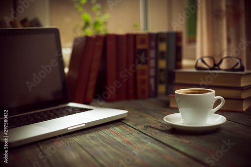 A cup of coffee in the workplace on a wooden table.