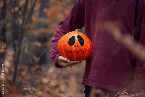 Boy holding in hands a Halloween spooky pumpkin.