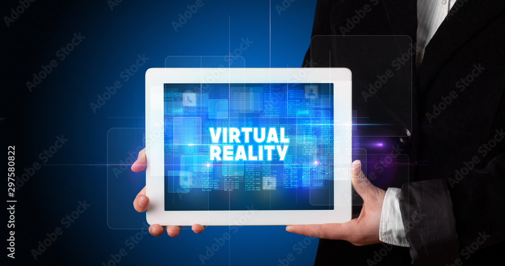 Young business person working on tablet and shows the inscription: VIRTUAL REALITY Young business person working on tablet and shows the inscription: VIRTUAL REALITY