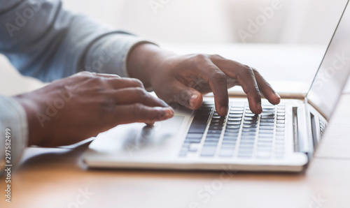 Unrecognizable african american man typing on laptop keyboard in office photo
