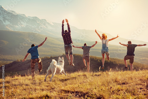 Group of friends runs and jumps in mountains photo