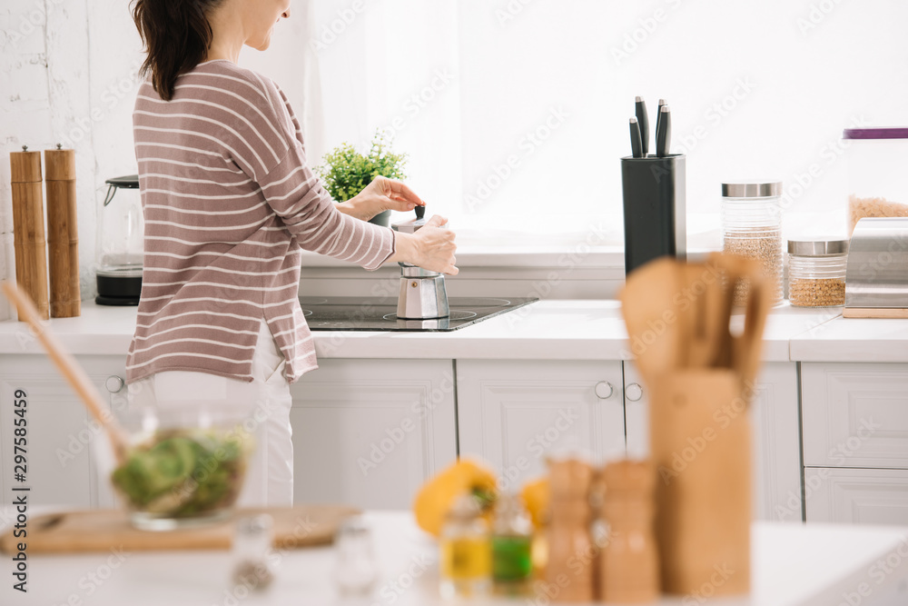 cropped view of young woman preparing coffee in geyser coffee maker