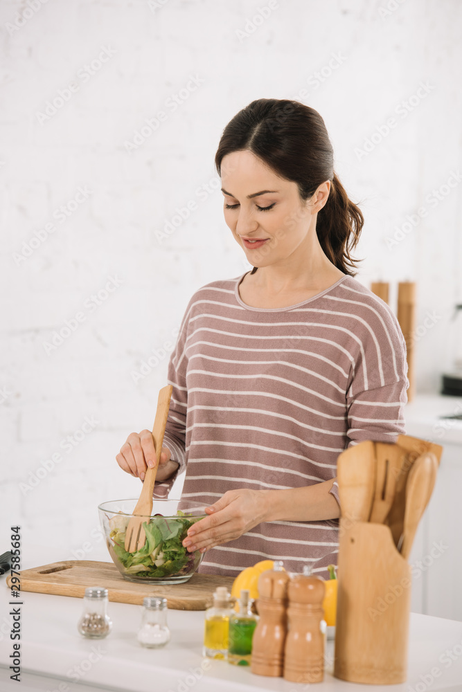beautiful young woman mixing fresh vegetable salad while standing at kitchen table beautiful young woman mixing fresh vegetable salad while standing at kitchen table