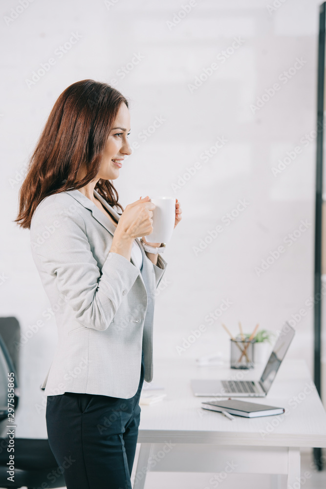 attractive, young secretary looking away while holding coffee cup attractive, young secretary looking away while holding coffee cup