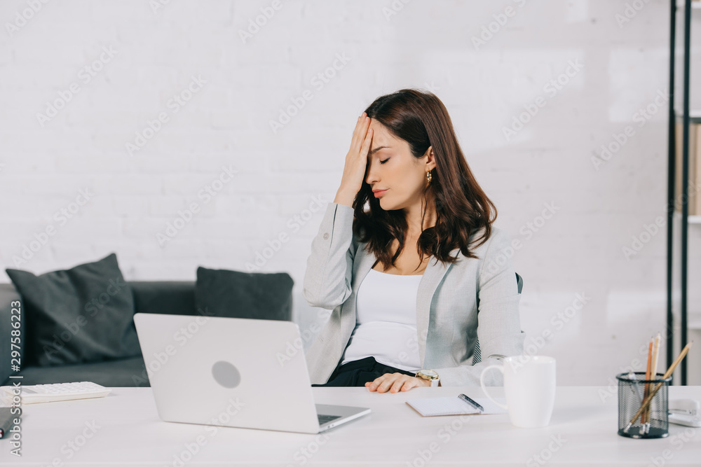 exhausted secretary suffering from headache while sitting at workplace and holding hand near head exhausted secretary suffering from headache while sitting at workplace and holding hand near head